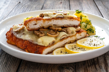 Crispy breaded seared chicken cutlet with fried white mushrooms, cheese and boiled potatoes on...