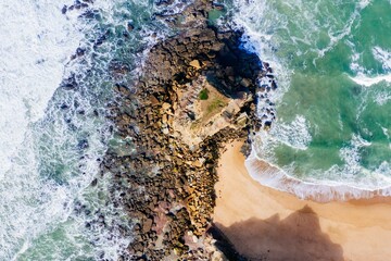 an aerial shot of sea waves washing up to the shore