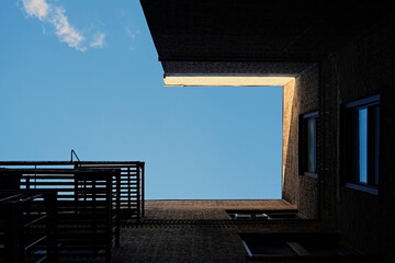 Surreal architectural abstraction of New York City tenement building framing blue sky
