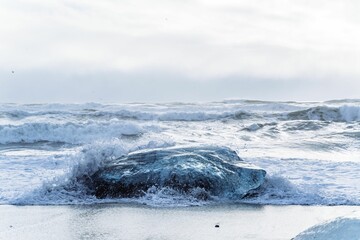 Waves coming in to the shore near a rocky shoreline - Powered by Adobe