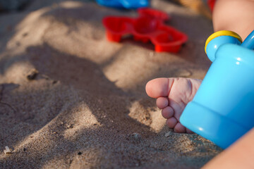 Cute foot with the fingers of a small child on the sand on the beach