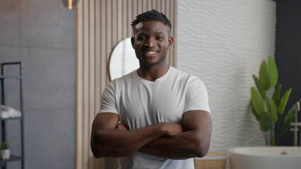 Portrait happy African American man ethnic hipster guy morning hygiene grooming procedures in hotel bathroom smiling confident male hands crossed posing in home bath toothy smile dental health service