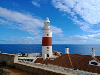 Fototapeta na wymiar Europa Point Lighthouse with the sea and a cloudy blue sky in the background in Gibraltar