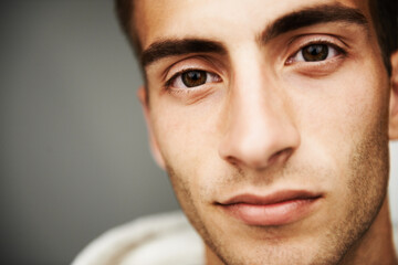 Portrait, male student and fashion with closeup in studio for cool, trendy or mockup for vision on gray background. Spain, young man and confidence with look on face for streetwear, clothes or casual