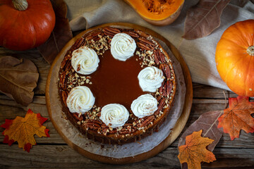 Pumpkin cheesecake. Curd cake with caramel, nuts, whipped cream, pumpkin, apples and autumn leaves on the background.