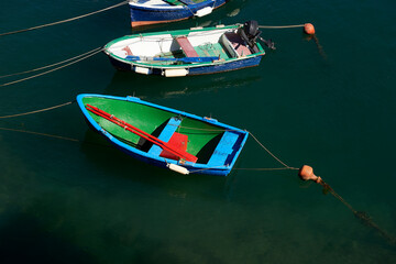 Fototapeta na wymiar small brightly colored boats with oars and outboard motor moored with buoys in the port