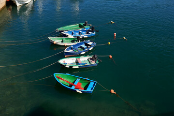 small brightly colored boats with oars and outboard motor moored with buoys in the port