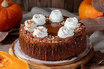 Pumpkin cheesecake. Curd cake with caramel, nuts, whipped cream, pumpkin, apples and autumn leaves on the background.
