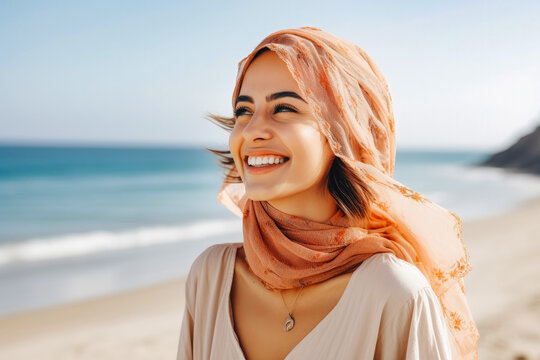 Happy beautiful young arab woman smiling at the beach. Summer at the beach, positivity and happy carefree lifestyle.