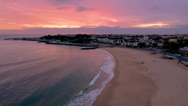 Aerial drone a view of the oceanfront city beach during a colorful romantic pink sunset, Lisbon, Portugal. High quality FullHD footage. 