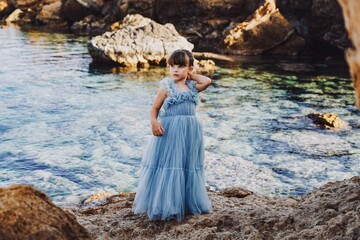 child in a blue dress on the beach in cyprus 