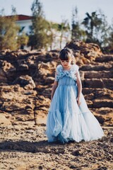 child in a blue dress on the beach in cyprus 