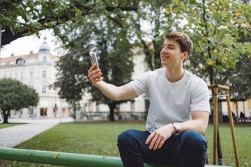 Young adult student using smart phone in park while going to school campus. Connected with friends everywhere, checking online bank, posting stories.