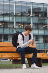 Young adult student using smart phone while going to school campus. Connected with friends everywhere, checking online bank, posting stories.