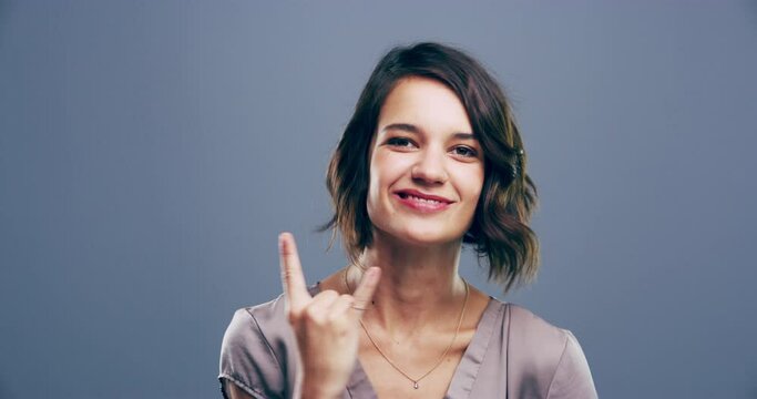 Rock, hand gesture or face of a crazy woman in studio on grey background for freedom, energy or emoji. Smile, model or portrait of cool person isolated for devil horns sign, punk or edgy attitude