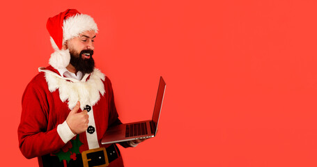 Bearded man in Santa Claus costume with laptop shows ok sign. Communication. Modern technology. Christmas shopping. Santa man with with notebook. Buy Christmas gift online. Copy space for advertising.