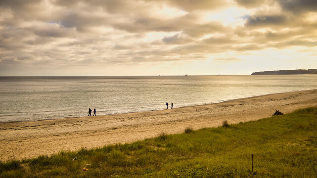 Blick &uuml;ber die D&uuml;nenlandschaft auf den herbstlichen Ostseestrand mit Spazierg&auml;ngern bei tiefstehender Sonne zwischen Sellin und Baabe, Insel R&uuml;gen, Deutschland