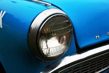 front headlight of a blue old car.