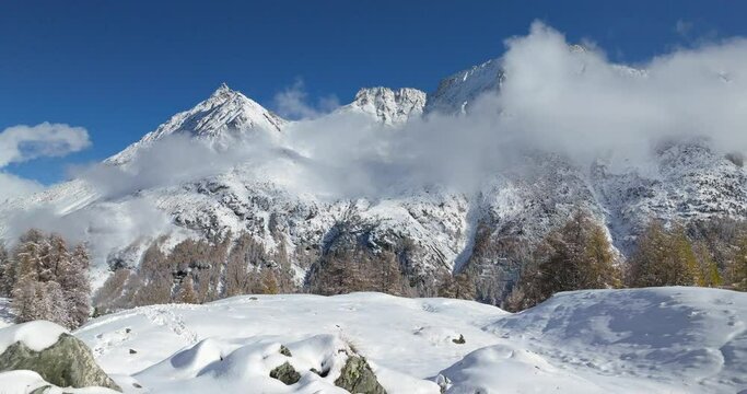 Lac Bleu Arolla lake frost in autumn colors in winter time snow covered Swiss mountains in Switzerland orange colors daylight flowing stream river aerial by drone