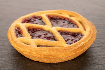 One shortbread with jam on a slate stone, close-up.