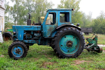 Photo of a blue old tractor on trees.