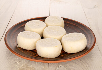 Several frozen semi-finished cheesecakes on a clay plate on a wooden table, macro.