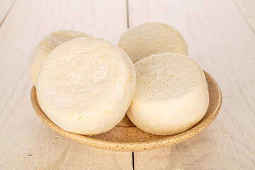 Several frozen semi-finished cheesecakes on a ceramic saucer on a wooden table, macro.