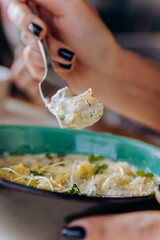 Close up of woman eating tasty Mussels in cheese sauce with dumplings served with greens