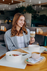 Young beautiful stylish woman drinking coffee while sitting in restaurant. Coffee break time