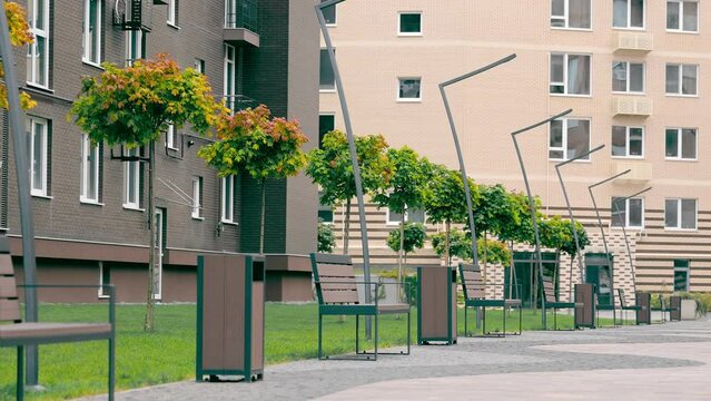 The outbuilding area near the new buildings is equipped with a green landscape and modern benches and lanterns. Rest area near residential complex.