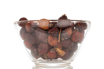 Several dry rosehip berries in a glass plate, macro, isolated on white background.