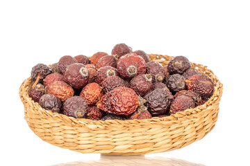 Several dry rose hips in a straw plate, macro, isolated on white background.