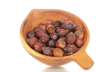 Several dry rosehip berries in a wooden cup, macro, isolated on white background.