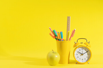 stationery, apple and retro alarm clock on a bright yellow background - Powered by Adobe