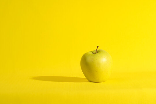 stationery, apple and retro alarm clock on a bright yellow background
