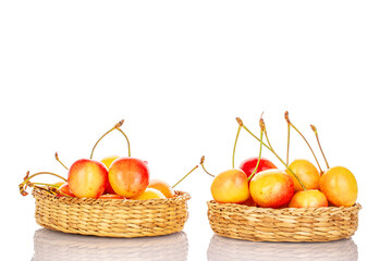 Ripe sweet yellow cherry berries in two straw plates, macro, isolated on white background.