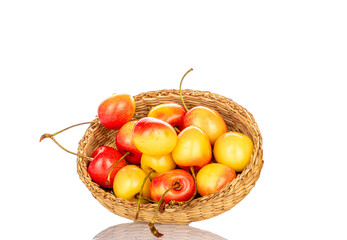 Ripe sweet yellow cherry berries in a straw plate, macro, isolated on white background.