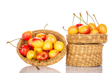 Ripe sweet yellow cherry berries in two straw plates, macro, isolated on white background.