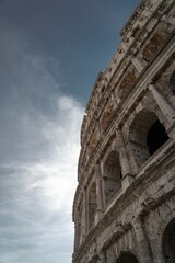 Vertical shot of the details of the Colosseum under a blue sky with clouds in Rome, Italy.
