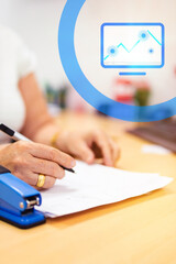 Fototapeta premium Latina woman, director of a bank, wearing a white blouse, working in her office. On her desk, there are documents, and she is writing with a pen in her hand. Additionally, a blue-colored statistical 