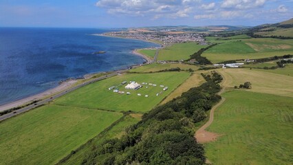 Aerial drone view of green fields with a blue seascape in Scotland in sunlight