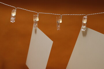 Kartki papierowe zawieszone na łańcuchu świetlnym z klamrami na pomarańczowym tle