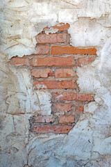 A stucco covered brick wall has lost some stucco exposing the brick wall behind