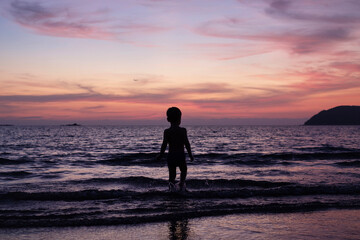 Fototapeta premium Child playing by the sea at sunset