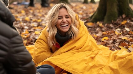 Happy woman sitting with yellow blanket in the forest in autumn season.