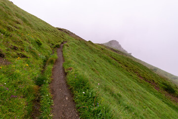 a landscape of Tatra mountains, a tourlit trail in the fog