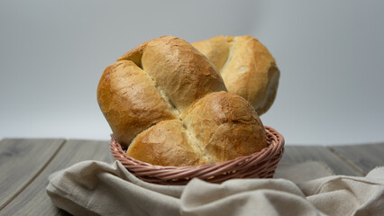 Traditional Chilean Marraqueta bread, in a bread basket with white background on gray wooden table.