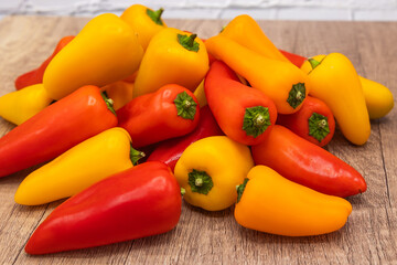 delicious and healthy red, orange and yellow sweet peppers on a wooden cooking board ready to be prepared in one recipe
