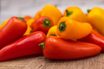 delicious and healthy red, orange and yellow sweet peppers on a wooden cooking board ready to be...
