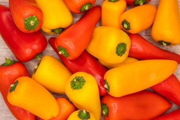 delicious and healthy red, orange and yellow sweet peppers on a wooden cooking board ready to be prepared in one recipe
